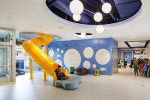 A picture of the yellow slide in the center of Discovery, with the blue Ocean-themed corridor in the background.